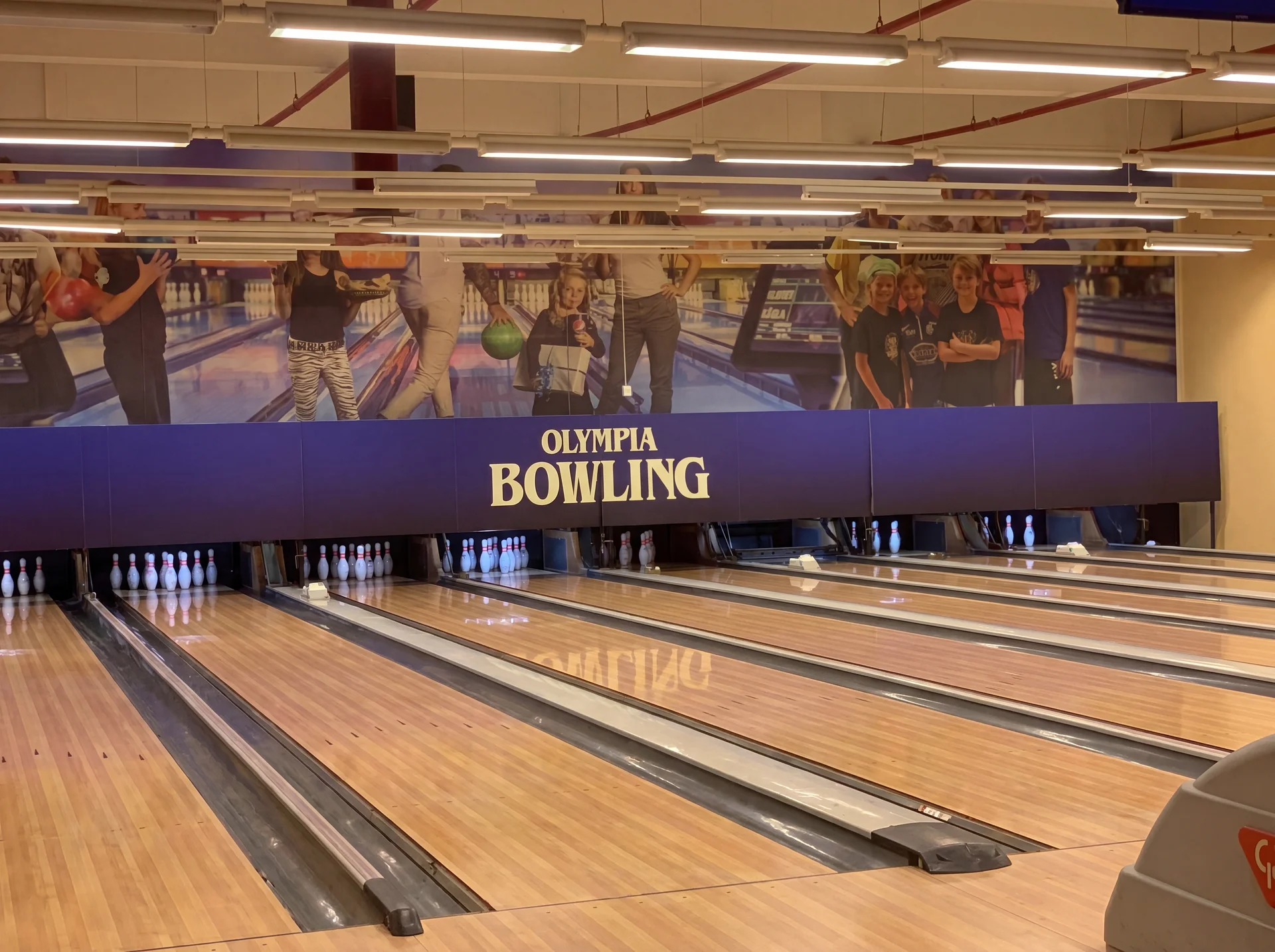 Bowlingbanor på Olympia Bowling med lila skylt och fotografier av spelare.